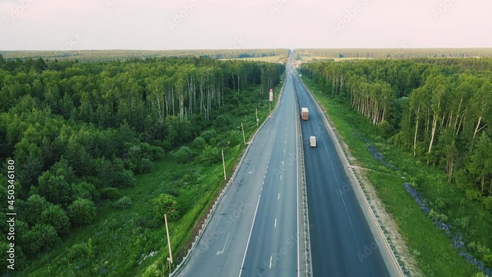 Aerial view of a small country road with moving cars. Transportation of goods as a business in the modern world. The concept of transport links between settlements, cities. UHD 4K. Aerial view of a small country road with moving cars. Transportation of goods as a business in the modern world. The concept of transport links between settlements, cities. UHD 4K.