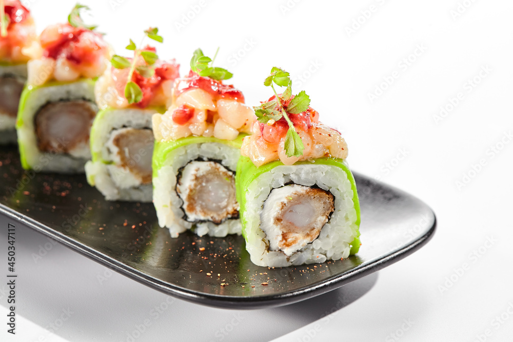 Shrimp Sushi Roll on black slate plate. Luxury maki sushi roll with cream cheese and shrimp inside. Seafood sushi roll topped with spicy scallop. Isolated on white background.