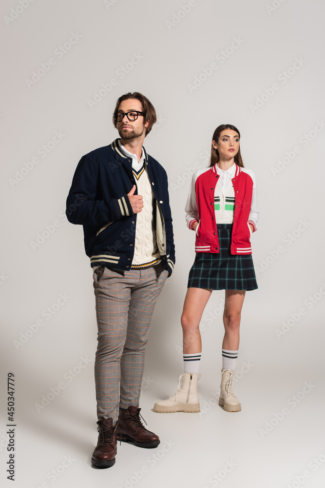 full length view of trendy couple in jackets and leather boots posing on grey background full length view of trendy couple in jackets and leather boots posing on grey background