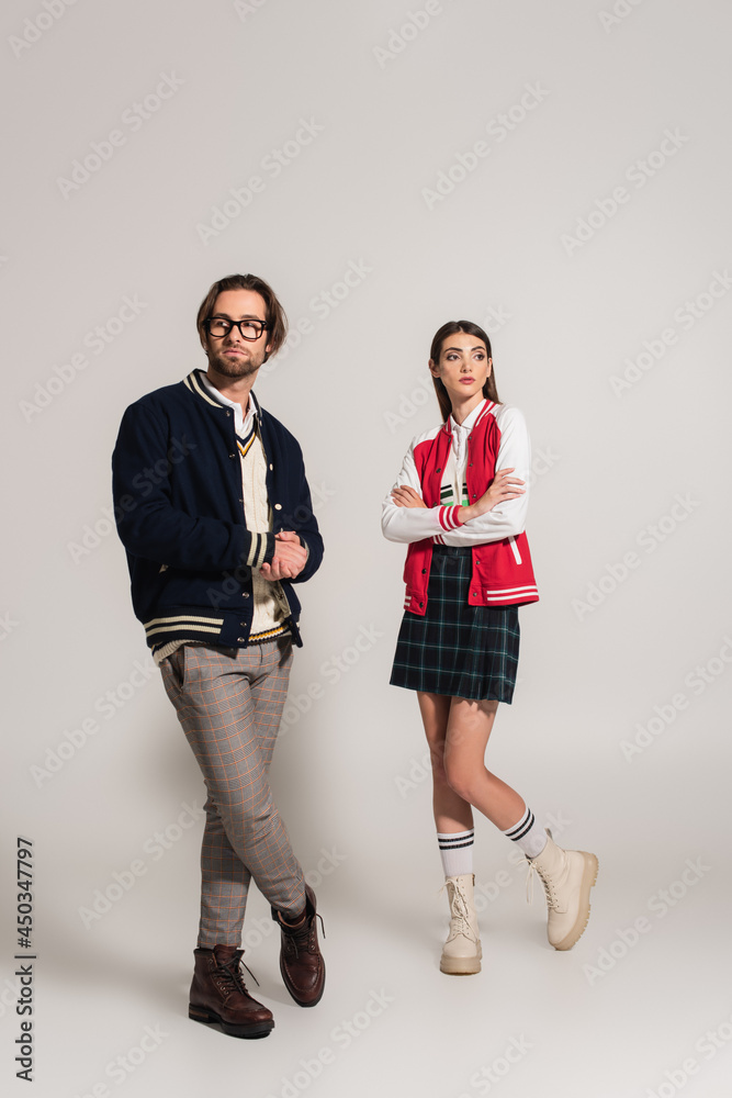 stylish woman standing with crossed arms near man in blue jacket on grey background stylish woman standing with crossed arms near man in blue jacket on grey background