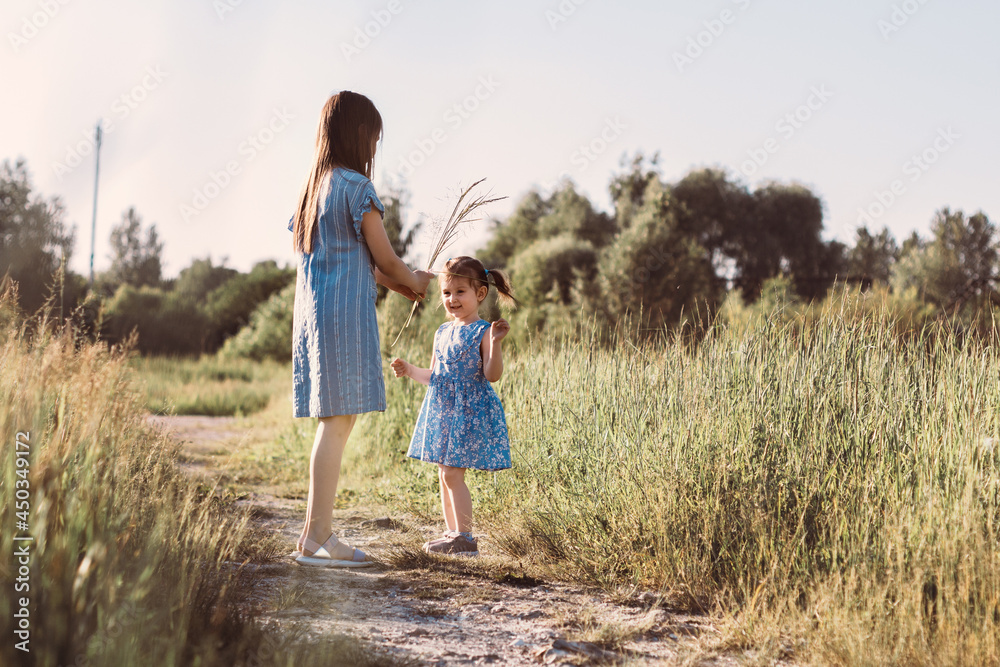 Two sisters walking in summer park with scenic path and playing. Two little girls looking at each other in green meadow Two sisters walking in summer park with scenic path and playing. Two little girls looking at each other in green meadow