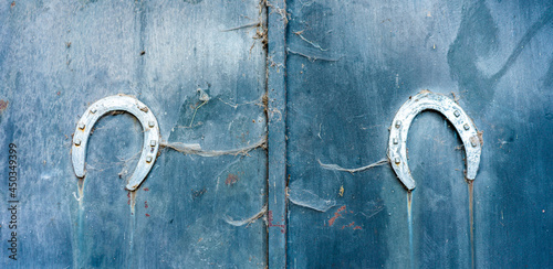 2 herraduras de metal sobre una puerta azul con texturas. como amuleto.
