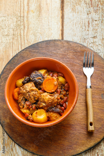 Jewish dish chelnt with meat on the table in a plate on a round wooden stand. photo