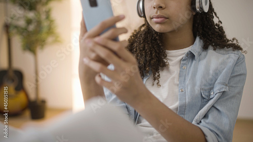 Teenage girl wearing headset using smartphone app, watching videos, scrolling media