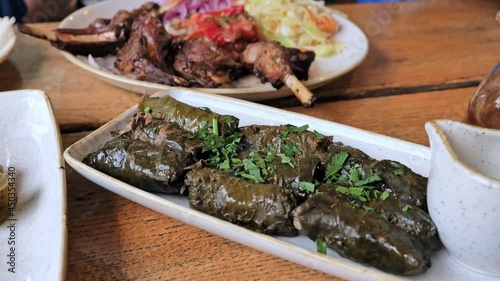Stuffed Greek Wine Grape Leaves (dolmades) with Roasted Lamb Chops Ribs with spices, vegetables. Selective focus photo