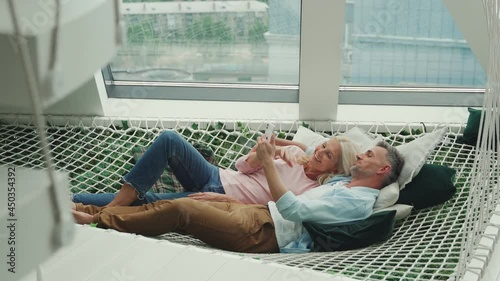 Mature couple communicating while relaxing in hammock at home together