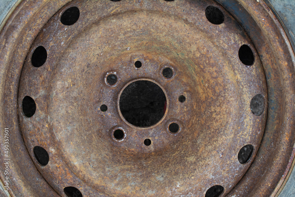 Old rusty car stamped wheel disc. Metal corrosion texture.