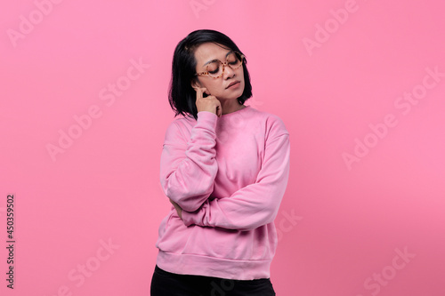 Portrait of Asian girl wearing pink jacket looking pensive, sad and unhappy