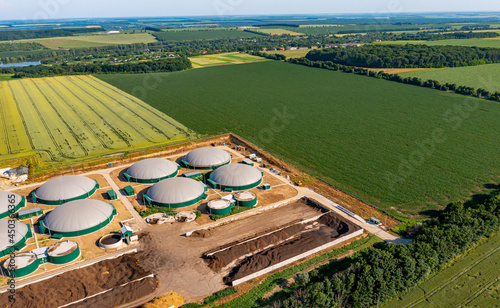 Biogas power station. Biogas plant for power generation and energy production around the green field. Agribusiness concept photo