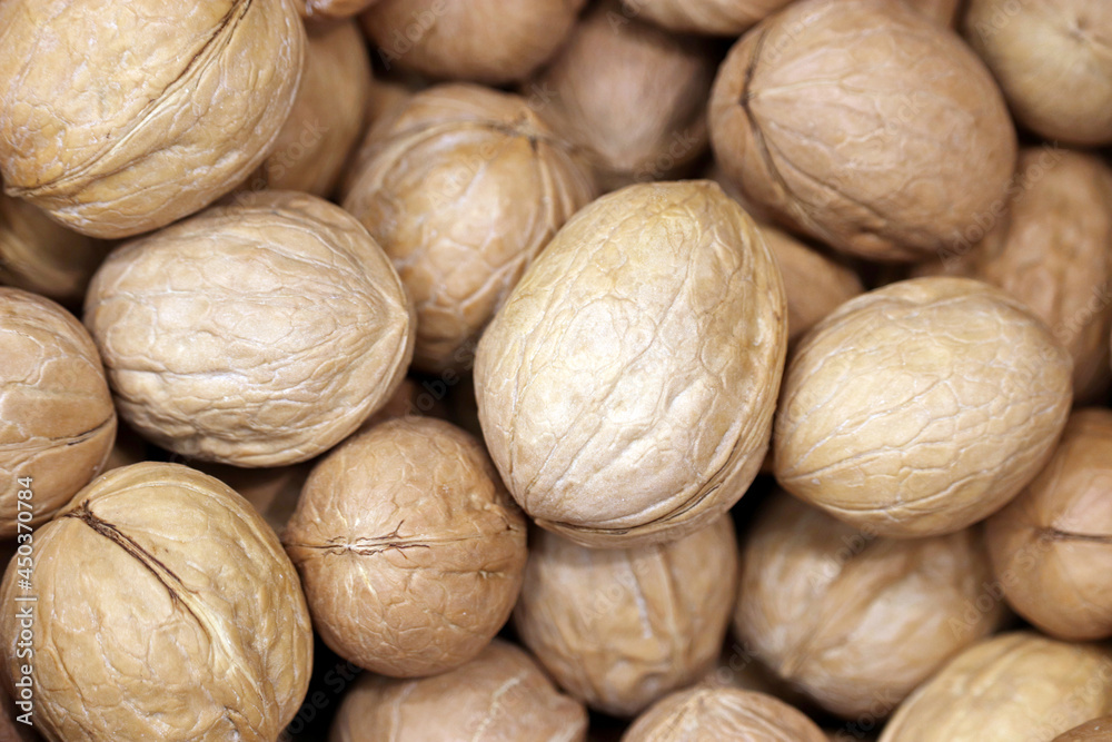Walnuts heap for background. Dry nuts in shells, protein food for brain health