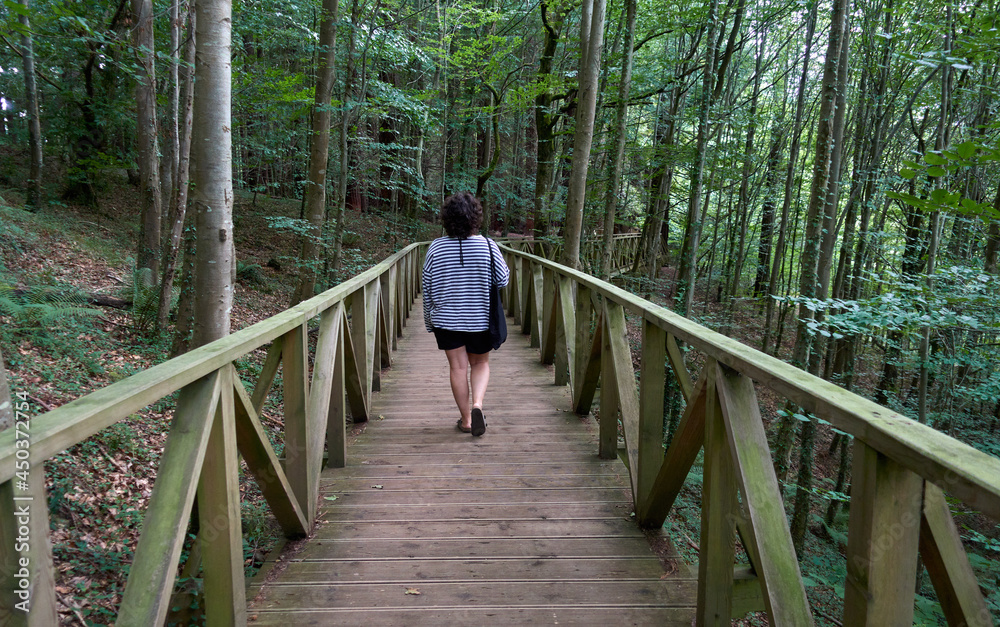 young woman walking along wooden walkway in the forest