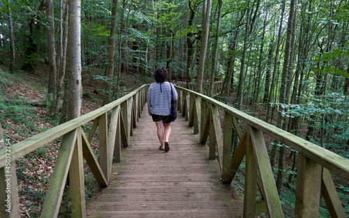 young woman walking along wooden walkway in the forest