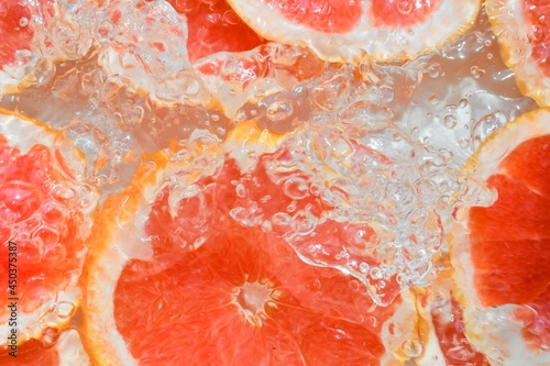 Slices of grapefruit in water on white background. Grapefruit close-up in liquid with bubbles. Slices of blood red ripe grapefruit in water. Macro image of fruits in water photo