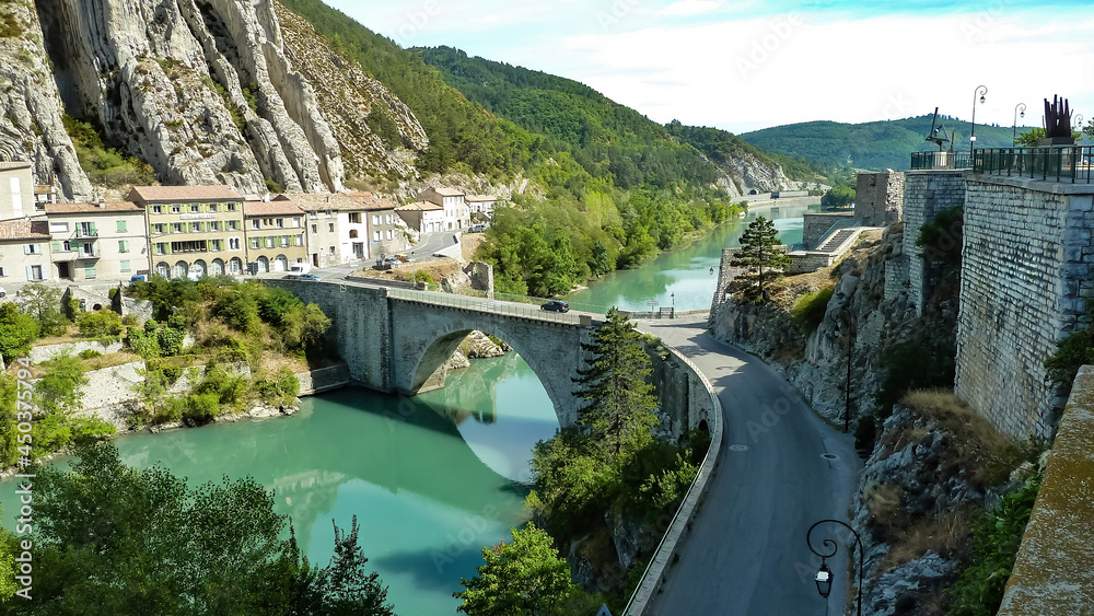 View on river durance with old bridge and village at food of mountain - Sisteron, Provence, France (focus on village left)
