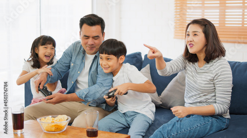 Young happy Asian family use joy controller  play video game together at home. Weekend holiday leisure party  people having fun  or home domestic activity lifestyle concept