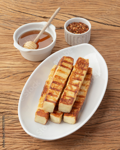 Grilled Rennet or Coalho cheese on a white plate with sugar syrup and pepper