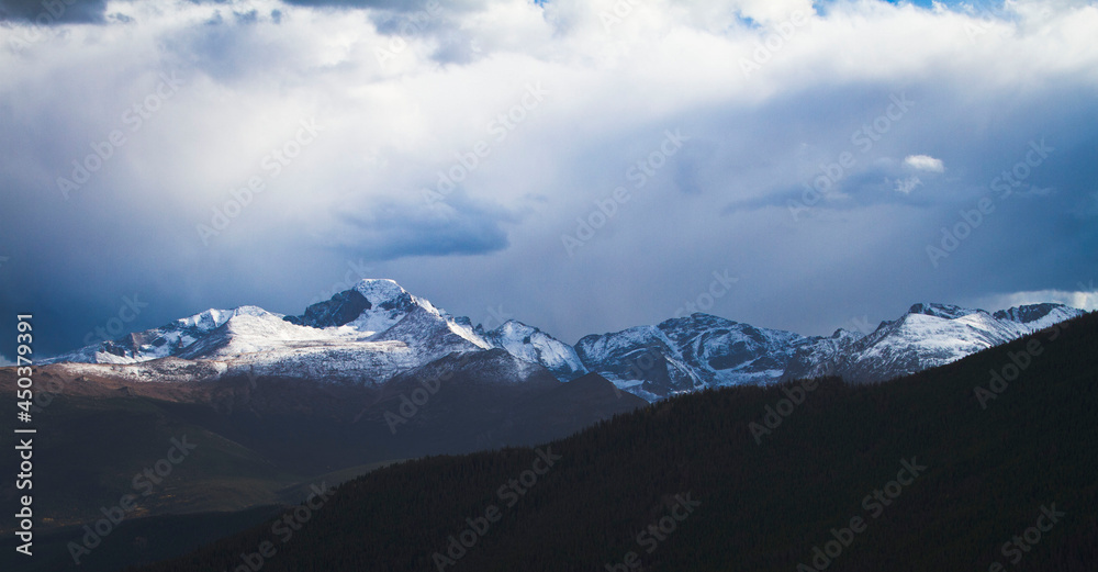 Light hitting snow capped mountains in Colorado, blue tones, moody atmosphere