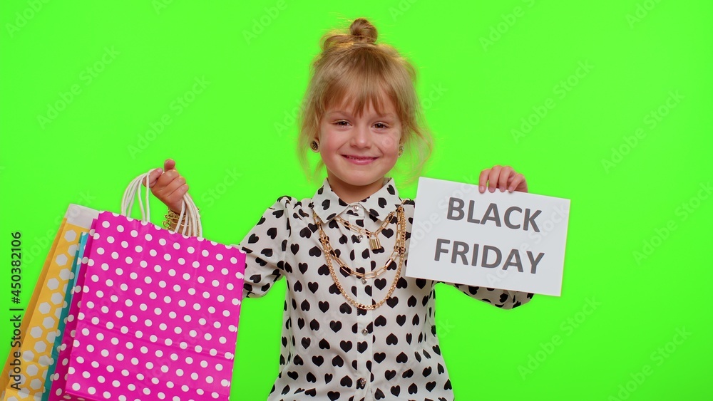 Fototapeta premium Little blonde kid child girl showing Black Friday inscription banner text, advertising discounts, smiling looking amazed with low prices, shopping on big sale day. Children on chroma key background