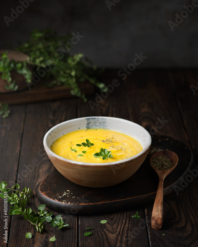 Vegetable puree soup on a dark wooden background. Pumpkin cream soup with thyme. Serving an autumn dish. Vegetarian food. Vegan cuisine. Dark style