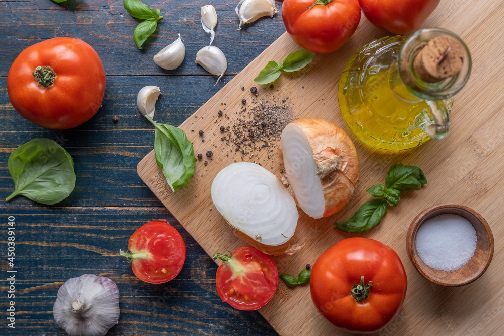 Preparing an Italian meal with a chopping board, tomatoes, garlic, oil, basil, cheese and salt Preparing an Italian meal with a chopping board, tomatoes, garlic, oil, basil, cheese and salt