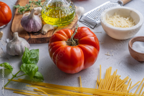 Preparing an Italian meal with a chopping board, tomatoes, garlic, oil, basil, cheese and salt
