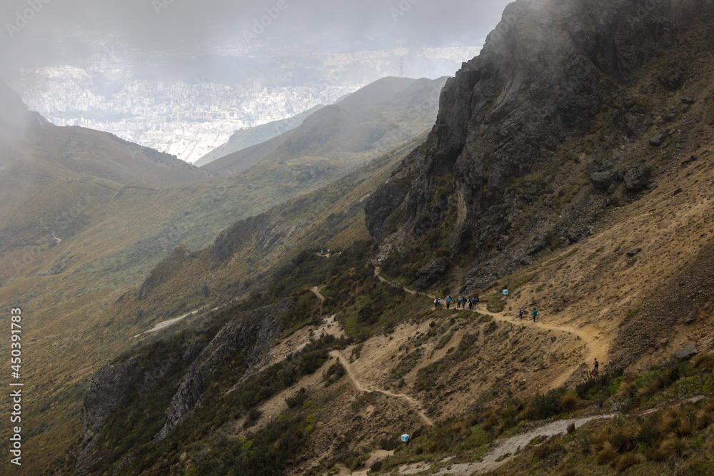 Hiking along the side of a volcano with downtown Quito, Ecuador in the