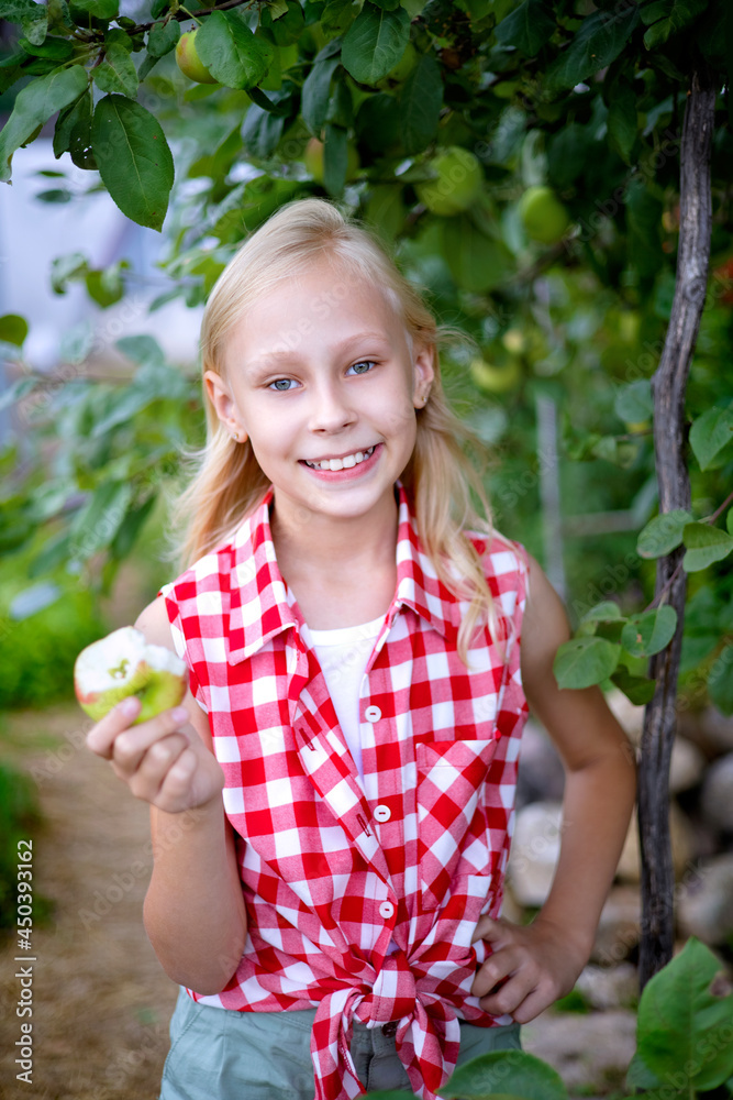A beautiful and happy blonde girl in an apple orchard A beautiful and happy blonde girl in an apple orchard