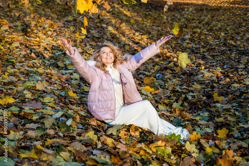 beautiful girl with blond hair in padded jacket on autumn leaves background, fall