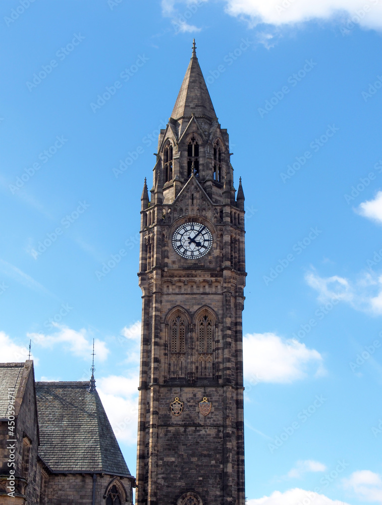 the tall clock tower of historic 19th century rochdale town hall in lancashire with blue summer sky and white clouds