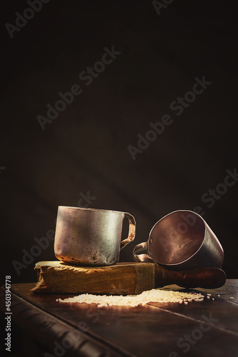 Closeup shot of two oldmetal cups on wood on the dark background photo