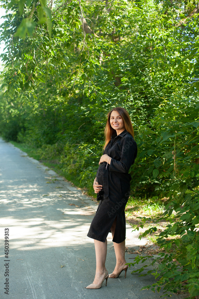 A beautiful stylish pregnant woman walks in the park. Fresh air, healthy lifestyle. Nature. A beautiful stylish pregnant woman walks in the park. Fresh air, healthy lifestyle. Nature.
