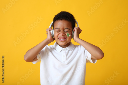 Funny Mexican boy listening to music on color background