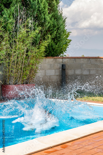  huge splash of water is created by a cannonball dive into a swimming pool © Marco Taliani