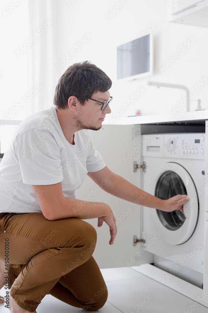 Young man putting clothes into washing machine Young man putting clothes into washing machine