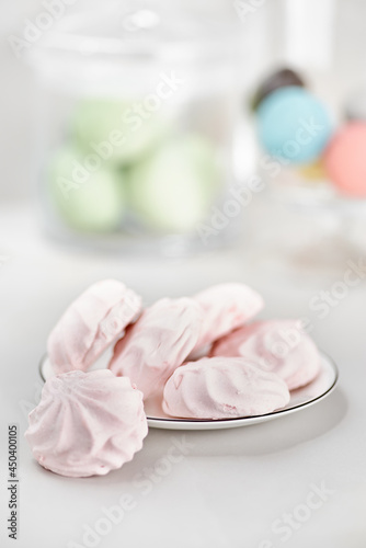 Delicate multi colored marshmallows on white plate. Still life with marshmallows pink on a light table.
