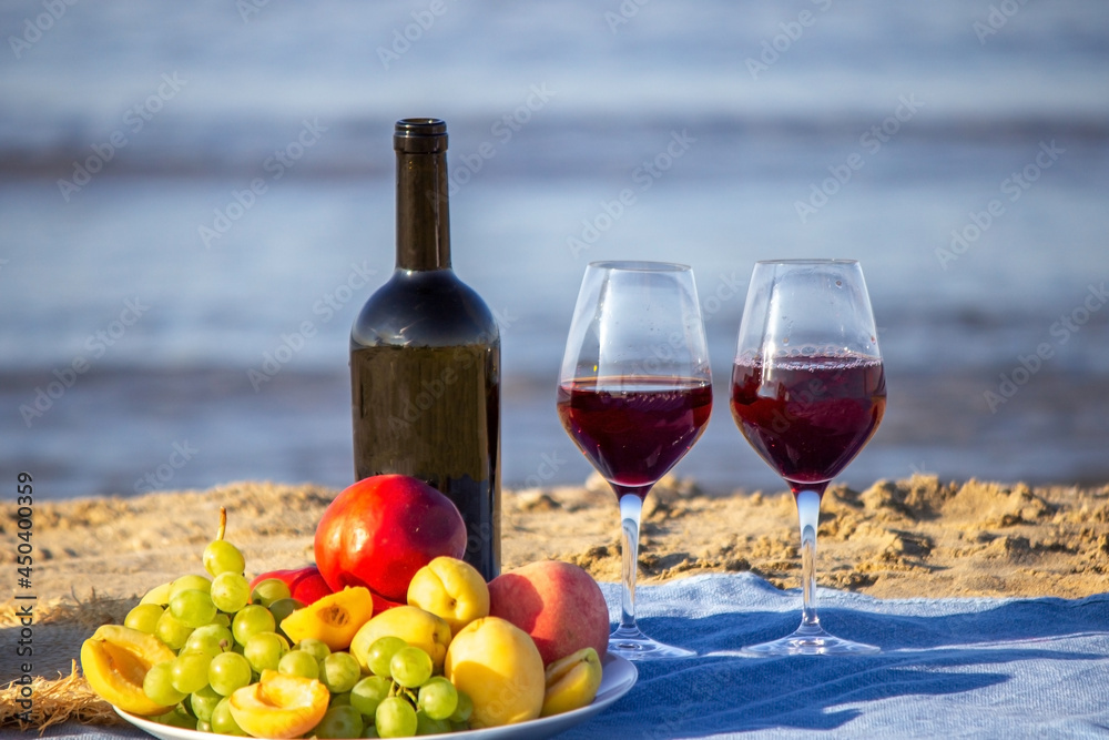 Obraz premium Picnic blanket, wine, fruit, beautiful sea beach. Selective focus