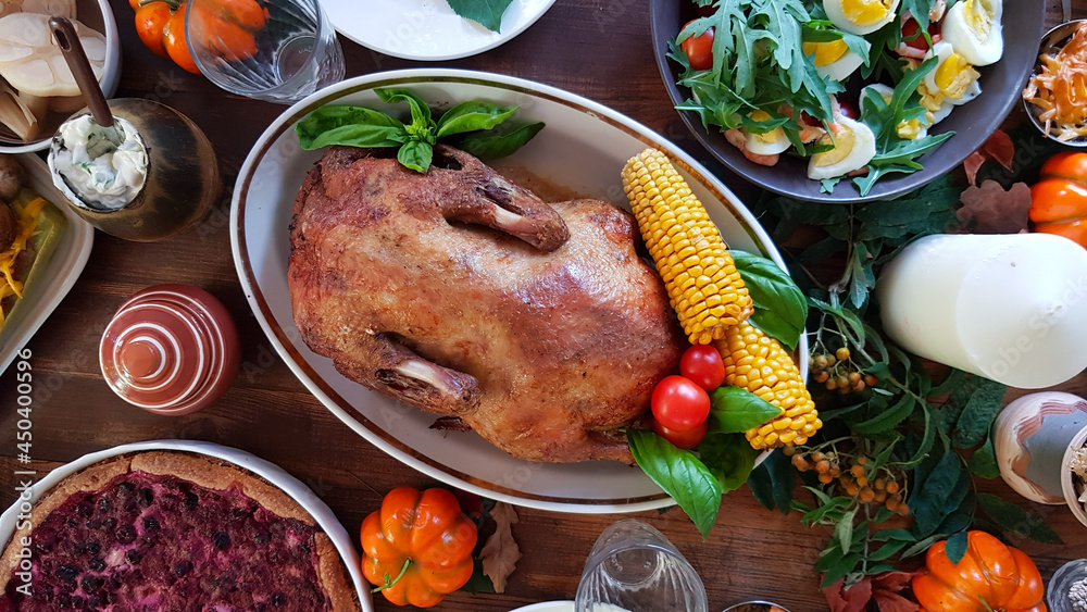 duck for a traditional family dinner in honor of the Thanksgiving holiday. beautifully set table with pumpkins, and autumn seasonal dishes.