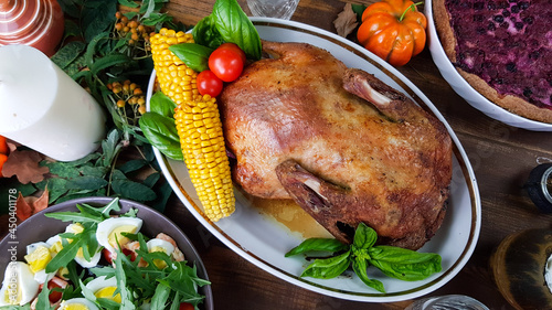a festive dish with goose for a traditional family dinner in honor of the Thanksgiving holiday. table with pumpkins and autumn seasonal dishes.