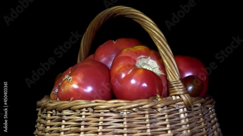 Vegetarian healthy food, composition of vegetables,  rotation of a basket with tomatoes on a black background