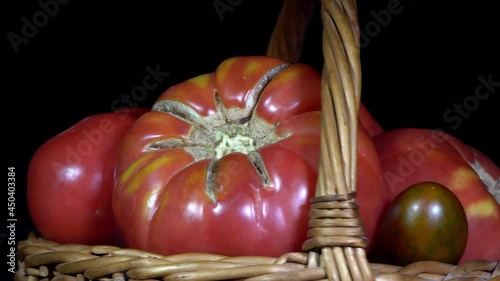 Vegetarian healthy food, composition of vegetables,  rotation of a basket with tomatoes on a black background