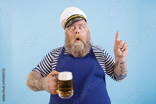 Принти на полотні Emotional mature sailor man with overweight in apron and captainhat holds beer a