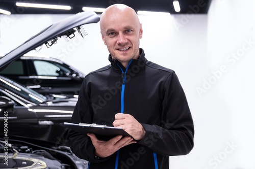 Car mechanic or car service owner checking car and filling documents
