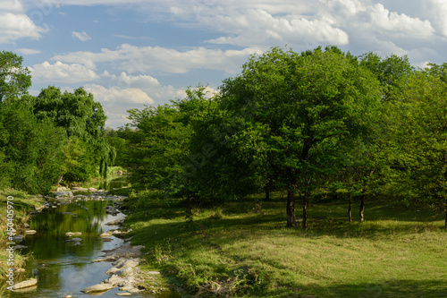 Arroyo en la verde pradera con hermoso cielo con nubes. Panorama