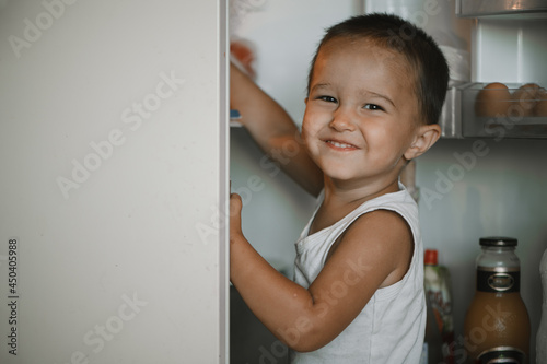 Tableau sur toile A child opens the refrigerator door at home in the kitchen