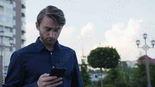 Close up man who stands and looks on his phone photo