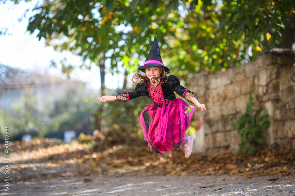 A little girl in a witch costume is jumping on the street. Halloween holiday. Copy space A little girl in a witch costume is jumping on the street. Halloween holiday. Copy space