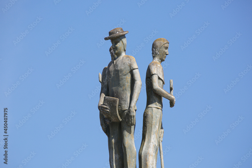 Statue on the side of a large and beautiful country road.
