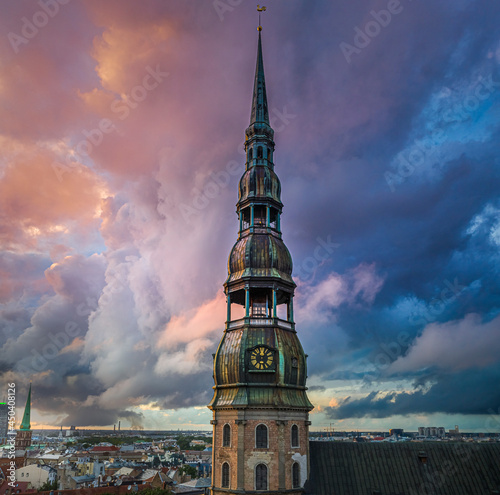 Incredible sunset over the Old town of Riga. Colorful sunlight shines over the rooftops of historic buildings and impressive church tower.