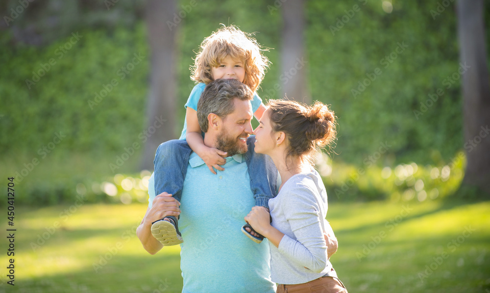 Fototapeta premium Happy family day. Mother and father carrying son on shoulders. Family day. Parents and boy child