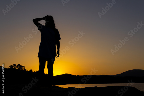 Silhouette of woman at sunset watching the horizon. Overcoming life's difficulties. Concept of reflection and thought. Selective focus. Copy space. Self-confidence. © Rodrigo